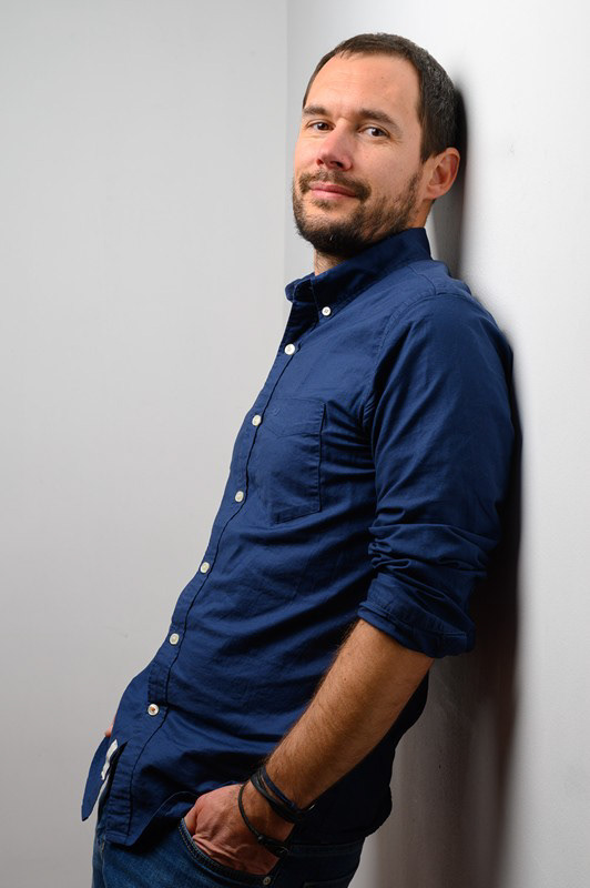 Portrait d’un homme en chemise bleue, les manches retroussées, sur fond clair